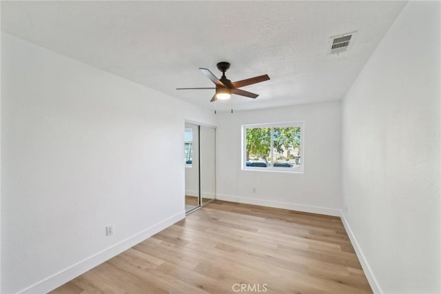 empty room with ceiling fan and light hardwood / wood-style flooring