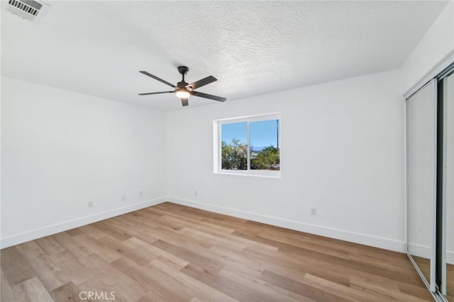 unfurnished bedroom with light wood-type flooring, ceiling fan, a textured ceiling, and a closet