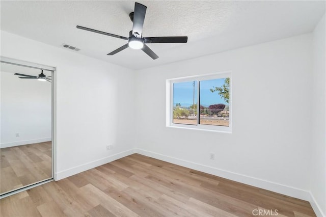 spare room with a textured ceiling and light wood-type flooring