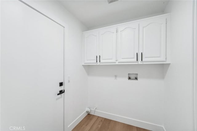 laundry area featuring cabinets, gas dryer hookup, hookup for a washing machine, and light hardwood / wood-style flooring