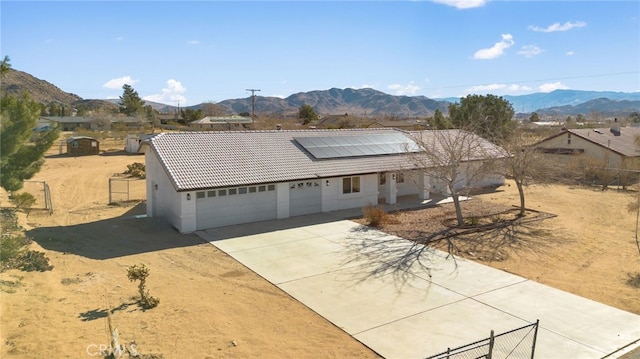 view of front of house with a garage, a mountain view, and solar panels