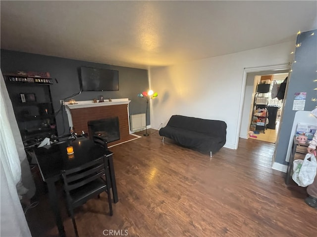 living room featuring dark hardwood / wood-style flooring and a brick fireplace