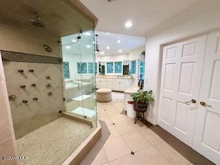 bathroom with crown molding, tile patterned flooring, and a tile shower