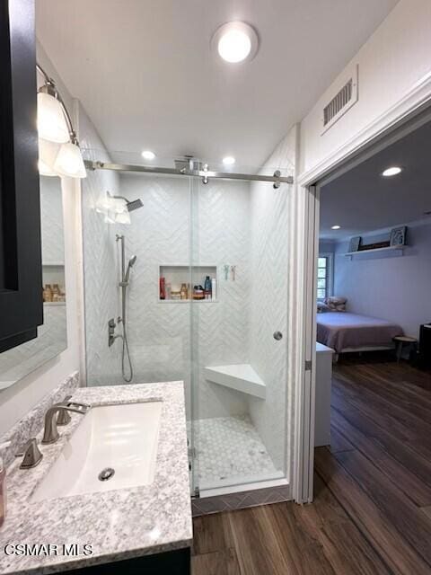 bathroom featuring hardwood / wood-style flooring, a shower with door, and vanity