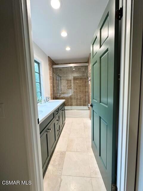 bathroom featuring tile patterned floors, tiled shower / bath, and vanity