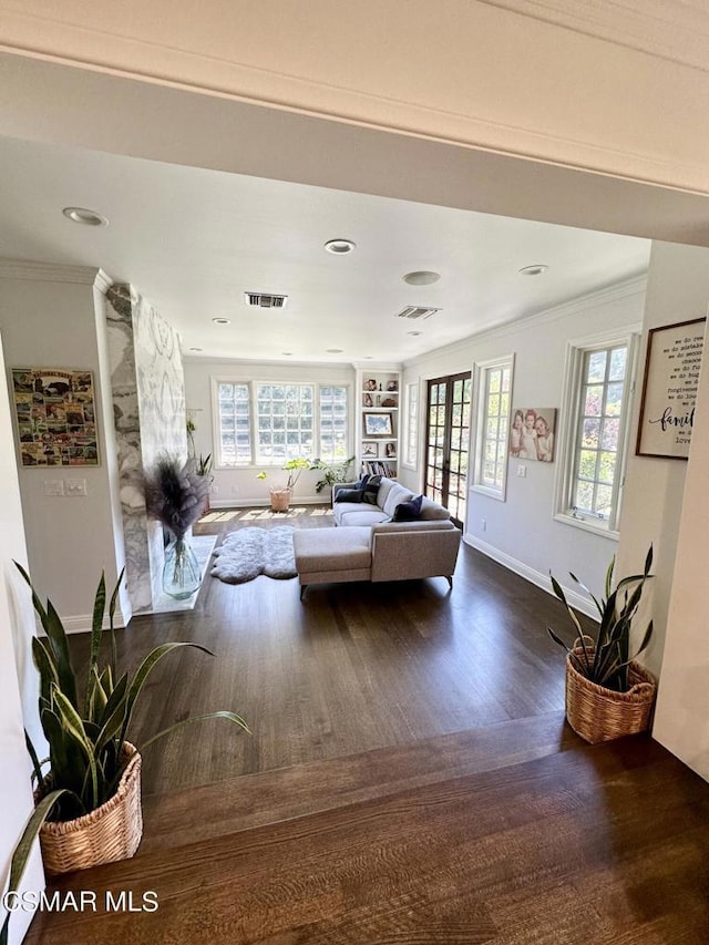 living room with dark hardwood / wood-style flooring, crown molding, and built in shelves