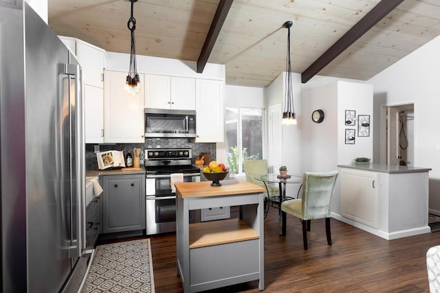 kitchen with dark hardwood / wood-style flooring, stainless steel appliances, lofted ceiling with beams, decorative light fixtures, and white cabinets