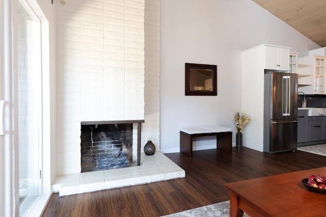 unfurnished living room with wooden ceiling, sink, a brick fireplace, vaulted ceiling, and dark hardwood / wood-style floors