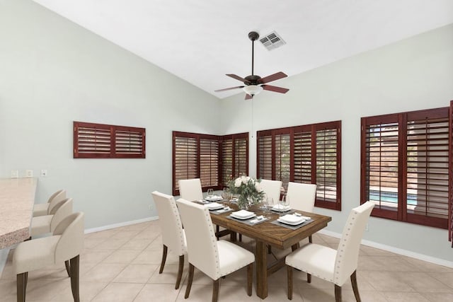 dining area featuring ceiling fan, light tile patterned floors, and a high ceiling