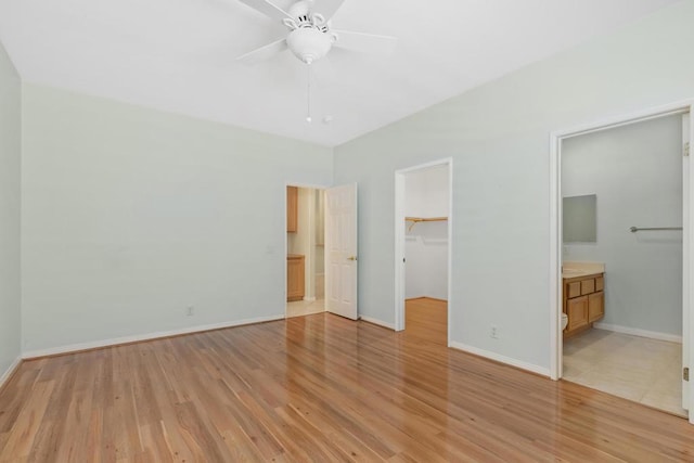 unfurnished bedroom with ensuite bathroom, light hardwood / wood-style flooring, a spacious closet, and ceiling fan