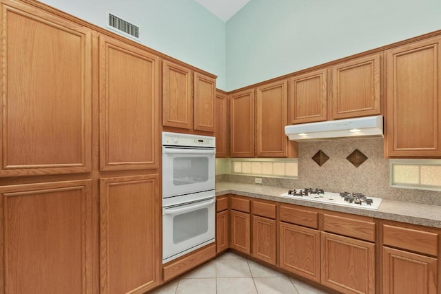 kitchen with white appliances, light tile patterned floors, and tasteful backsplash