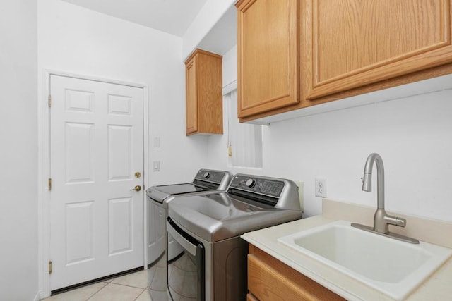 washroom with washing machine and dryer, sink, light tile patterned floors, and cabinets