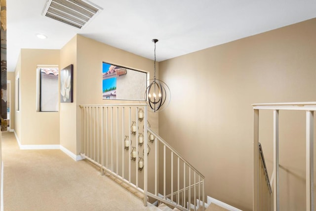 stairway with carpet flooring and a notable chandelier