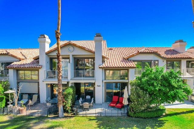 back of house featuring a patio, a balcony, and a lawn