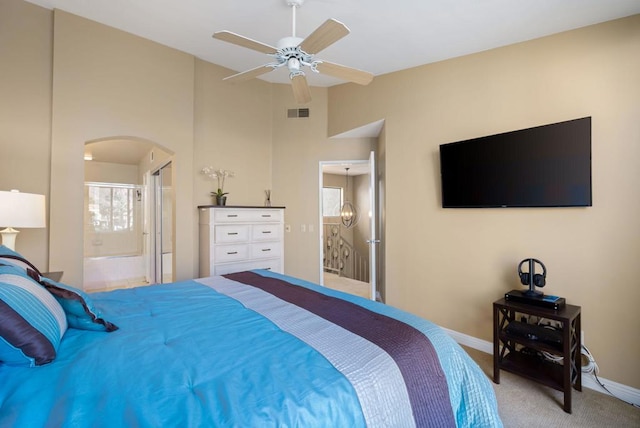 carpeted bedroom featuring a towering ceiling, ensuite bath, and ceiling fan