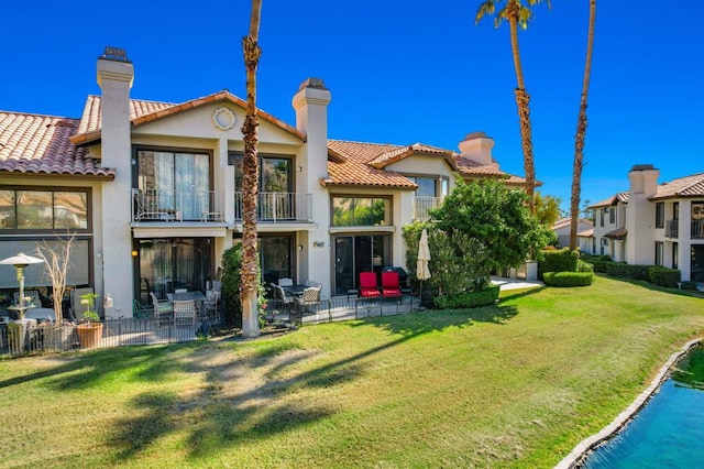 rear view of property featuring a balcony, a yard, and a patio