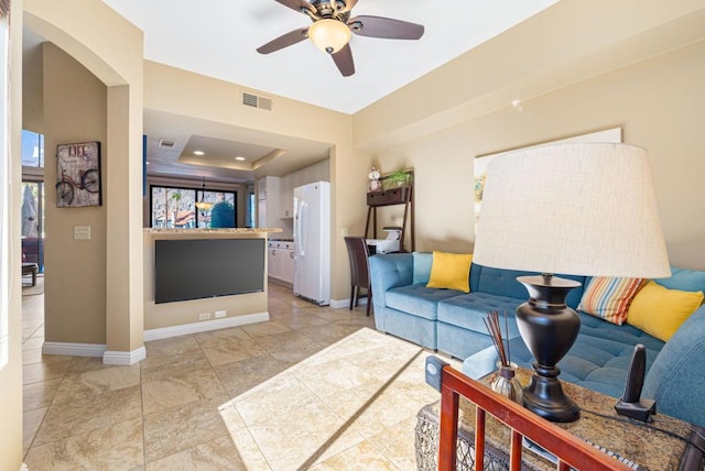 living room featuring ceiling fan and a tray ceiling