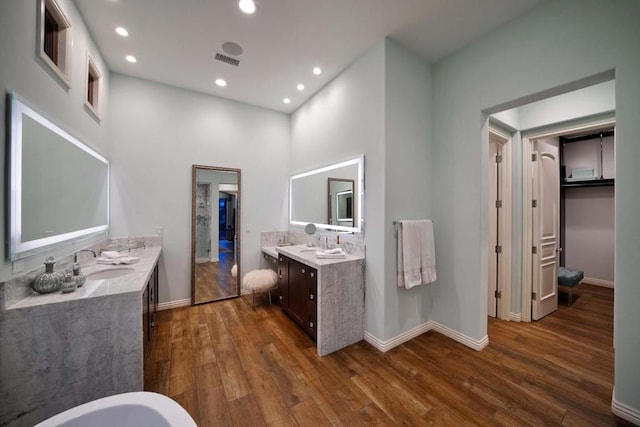 bathroom featuring vanity, wood-type flooring, and a high ceiling