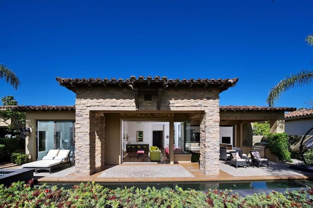 rear view of property featuring a patio and an outdoor kitchen