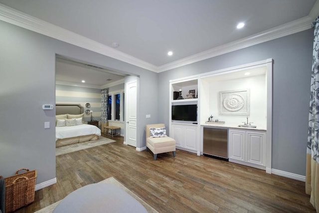 bedroom featuring stainless steel refrigerator, crown molding, hardwood / wood-style floors, and sink