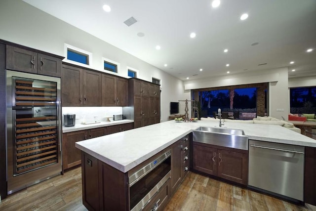 kitchen with dark brown cabinets, stainless steel appliances, beverage cooler, dark wood-type flooring, and sink