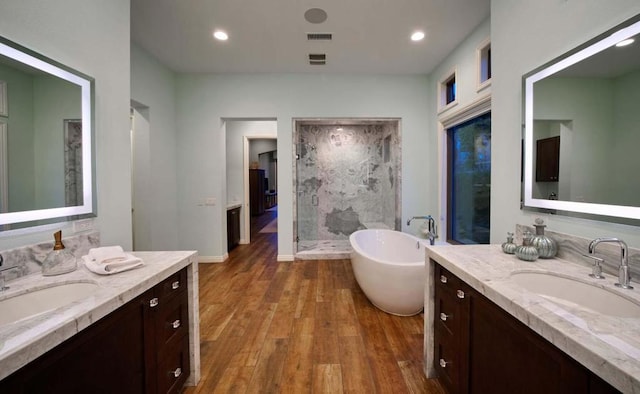 bathroom with wood-type flooring, vanity, and shower with separate bathtub