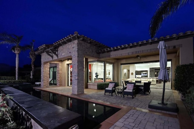 patio at night featuring ceiling fan and an outdoor hangout area