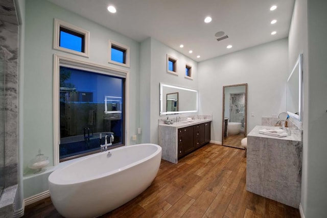 bathroom with hardwood / wood-style flooring, vanity, shower with separate bathtub, and a high ceiling