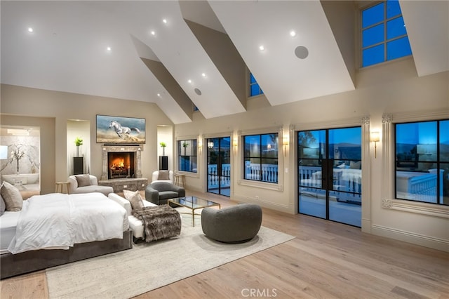 bedroom with access to outside, light hardwood / wood-style floors, and high vaulted ceiling