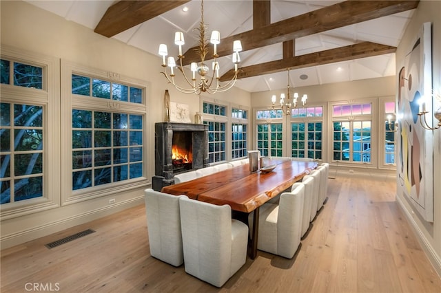 dining room with high vaulted ceiling, beam ceiling, a high end fireplace, and an inviting chandelier