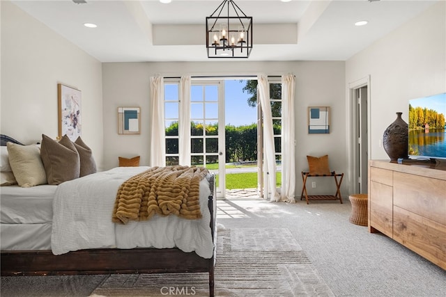 bedroom with carpet floors, access to outside, a tray ceiling, and a chandelier