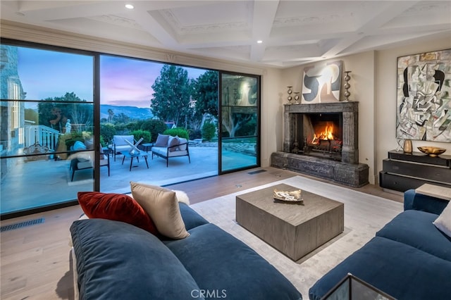 living room with light wood-type flooring, a fireplace, coffered ceiling, and beamed ceiling