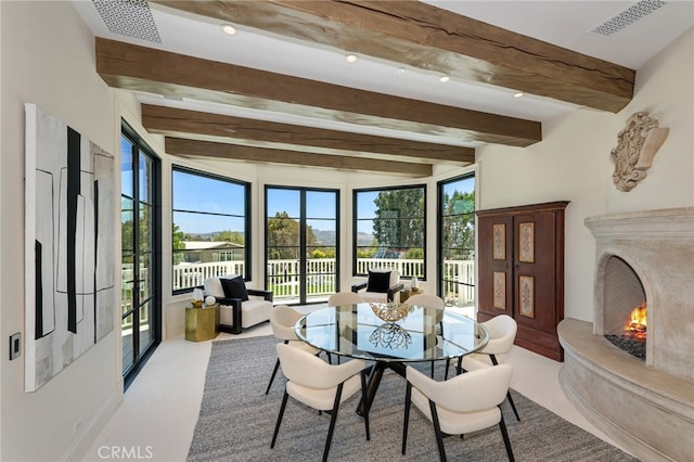 dining area with beamed ceiling, a fireplace, and a healthy amount of sunlight