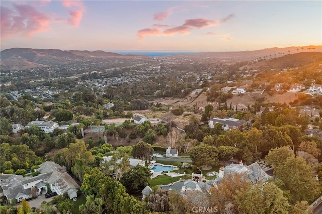 aerial view at dusk featuring a water and mountain view