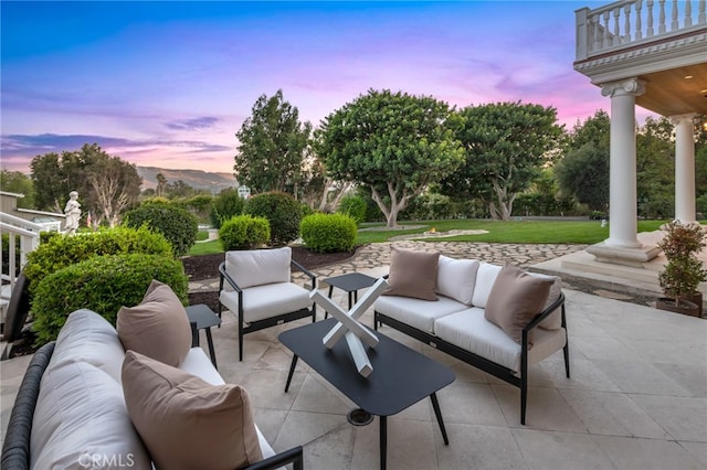 patio terrace at dusk featuring a balcony, an outdoor hangout area, and a mountain view