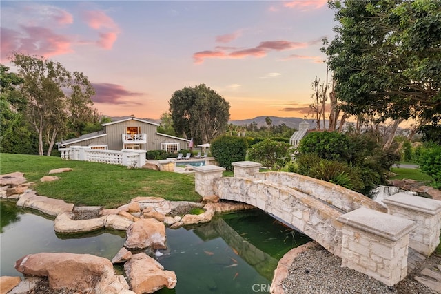 pool at dusk with a lawn, a mountain view, and a garden pond