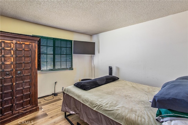 bedroom featuring light wood-type flooring and a textured ceiling