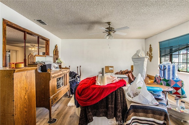 living room with wood-type flooring, ceiling fan, and a textured ceiling