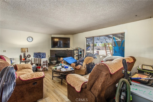 living room featuring a brick fireplace, a textured ceiling, and light wood-type flooring