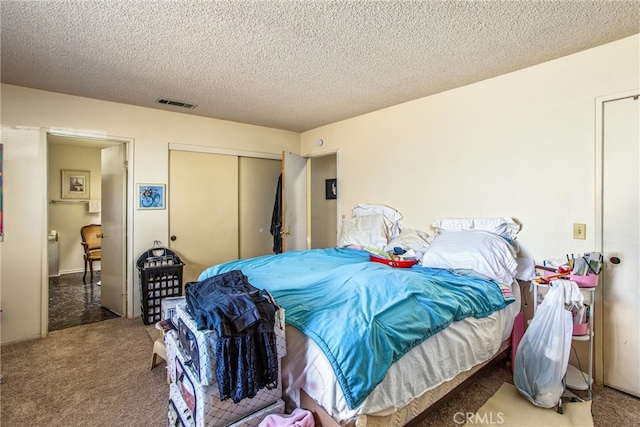 bedroom with a closet, carpet flooring, and a textured ceiling