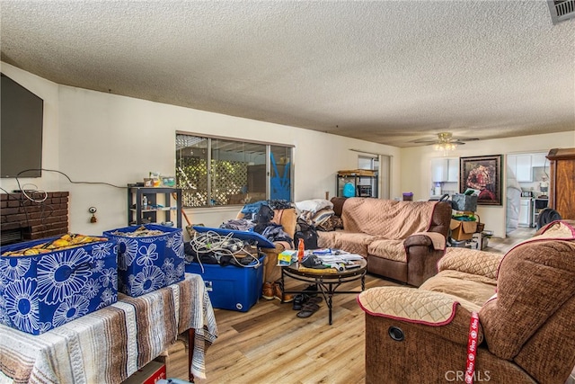 living room featuring ceiling fan, a textured ceiling, and light hardwood / wood-style floors