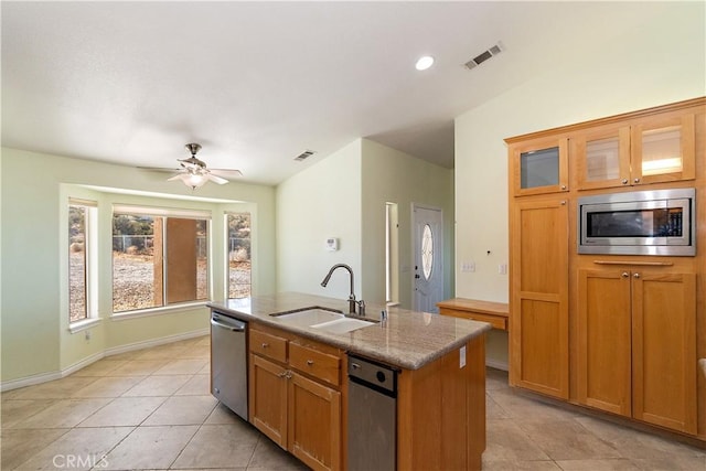 kitchen featuring a kitchen island with sink, sink, ceiling fan, light stone countertops, and stainless steel appliances