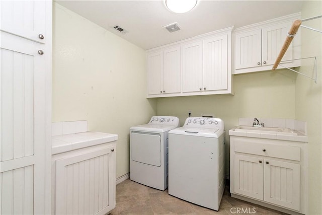 clothes washing area featuring sink, cabinets, and independent washer and dryer