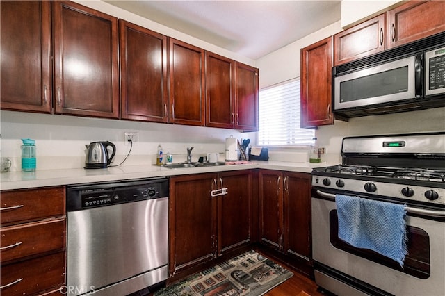 kitchen with appliances with stainless steel finishes, dark hardwood / wood-style flooring, and sink