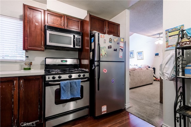 kitchen with appliances with stainless steel finishes, a textured ceiling, dark hardwood / wood-style flooring, and ceiling fan