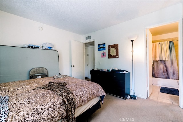 carpeted bedroom featuring a textured ceiling and ensuite bathroom