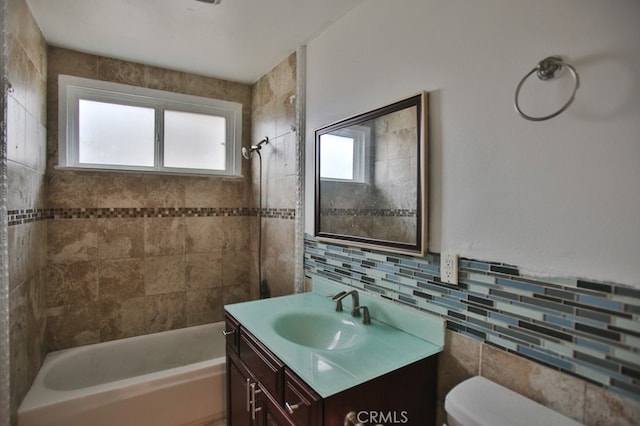 full bathroom featuring tiled shower / bath, vanity, tile walls, and toilet