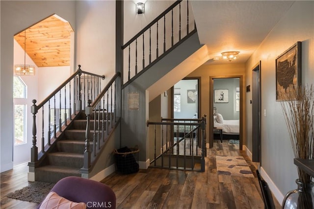 stairs with an inviting chandelier, wooden ceiling, and hardwood / wood-style flooring