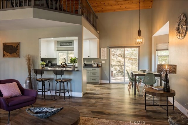 kitchen featuring white cabinets, kitchen peninsula, hanging light fixtures, and high vaulted ceiling