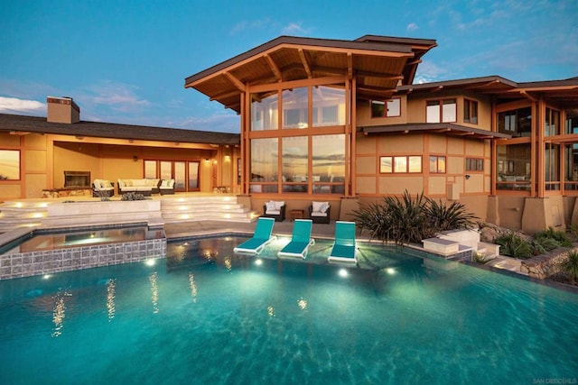 pool at dusk featuring an in ground hot tub